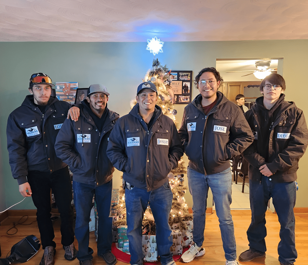Five men posing in front of Christmas tree